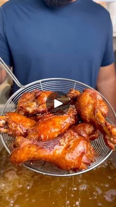 a man holding a basket full of chicken wings