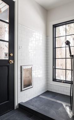 a black and white tiled bathroom with a shower head in the corner next to an open door