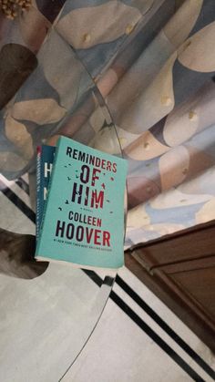 a book sitting on top of a glass table next to a wallpapered ceiling