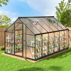 a small greenhouse in the middle of a yard with lots of plants growing inside it