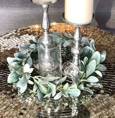 two silver candles are sitting on a glass plate