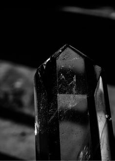 a black and white photo of a crystal on the ground with drops of water all over it