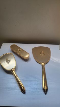 three golden spoons and a brush on a table