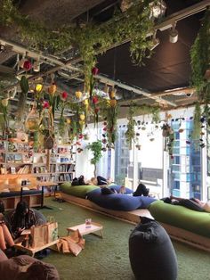 people are sitting on bean bags in the middle of a room with plants hanging from the ceiling