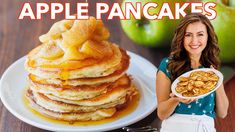 a woman holding a plate with pancakes on it and an apple in the back ground