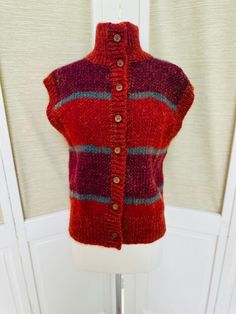 Vintage Jennifer Reed mohair sweater vest.  Sleeveless, brown wooden buttons to the neck.  Burnt orange, maroon and blue with stripes. Great fall colors!  Women's size medium.  In good vintage condition with no stains or holes. 22" long 18.5" armpit to armpit Shipping: USPS Standard Post (insurance tracking included) We are happy to ship internationally! *Due to the variability in shipping costs based on location, anything in excess of $2.00 over the actual cost will be refunded.  We can provide a combined shipping cost and/or estimate to your location. Refunds and Exchanges: All sales are final.  You will not be refunded if an item does not fit. Please check the measurements carefully and ZOOM into photographs to view details.  Please ask any questions prior to purchase.  Thanks! Thank yo Brown Buttoned Vest For Winter, Brown Buttoned Sweater Vest For Fall, Brown Winter Vest With Buttons, Knitted Wool Vest For Fall, Casual Wool Vest With Buttons, Red Wool Vest For Winter, Wool Sweater Vest With Buttons For Fall, Jennifer Reed, Striped Sweater Vest