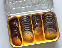 a tin filled with lots of coins sitting on top of a white table next to a yellow container