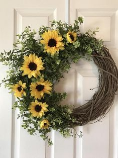 a wreath with sunflowers hanging on the front door