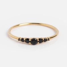 a gold ring with three black stones on the side and two small diamonds in the middle