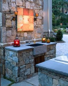 an outdoor kitchen is lit up with candles and lights on the side of the building