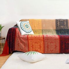 a living room with a couch covered in blankets and pillows on top of white rugs