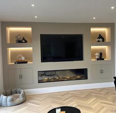 a living room with a large television mounted on the wall and shelves above it that are lit up