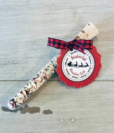 a candy bar wrapped in red and black paper with a ribbon around it on a wooden surface