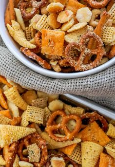 two bowls filled with cheetos and pretzels on top of each other