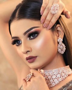 a woman with dark makeup and jewelry on her hand, posing for a photo in front of the camera