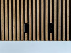 two black electrical outlets are mounted to the side of a wooden wall with vertical slats