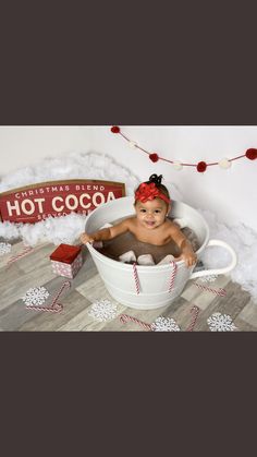 a baby sitting in a hot cocoa tub surrounded by christmas decorations