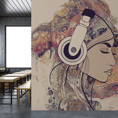 a woman with headphones on her ears in front of a wall mural that has an image of a woman's face