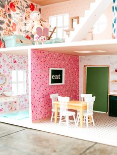 a doll house with pink and green walls, white chairs and table in the middle