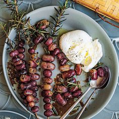 a plate full of food with eggs and olives on it, next to utensils