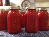 four jars filled with red sauce sitting on top of a table