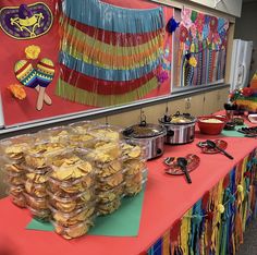 a table filled with lots of food on top of a red table cloth covered table