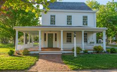 a white two story house sitting on top of a lush green field