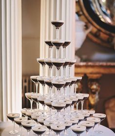 a stack of wine glasses sitting on top of a table next to a white column