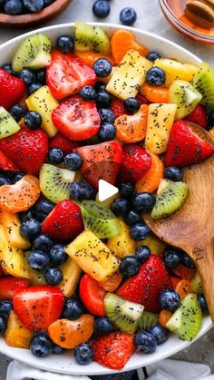 a bowl full of fruit with a wooden spoon