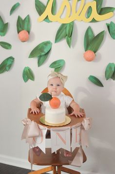 a baby sitting in a high chair next to a cake