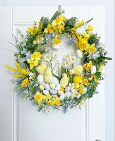 a wreath with yellow and white flowers on the front door