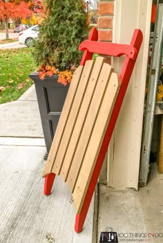 a wooden sled sitting on the side of a building next to a potted plant