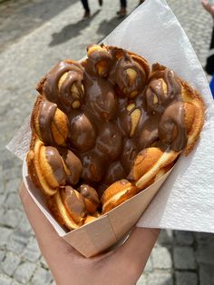 a person holding a pastry with chocolate icing on it