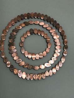 three different types of coin necklaces on a gray surface, one is brown and the other is silver