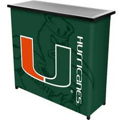 The officially licensed University of Miami Portable Bars for Events by Trademark Gameroom will ensure your next picnic or BBQ is a hit. This bar cabinet features an officially licensed cover and two sturdy shelves which provide more than enough space for all your drinks and bar accessories. The pub table is made of durable metal with four strong legs that collapse and stores compactly into the included carrying bag for effortless travel and space-saving storage, great for apartments and small h Miami Logo, Bar Portable, Portable Bar, Blue Bar, Wine Bottle Rack, Home Bar Furniture, Strong Legs, Outdoor Bar Table, Two Shelves