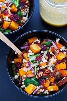 two bowls filled with food next to a jar of dressing