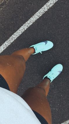 a person standing in the middle of a parking lot with their feet up and wearing blue shoes