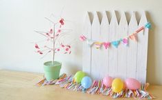 a wooden fence with easter eggs and a potted plant on the table next to it