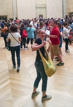 a large group of people standing in a room with wooden floors and walls, all looking at the camera