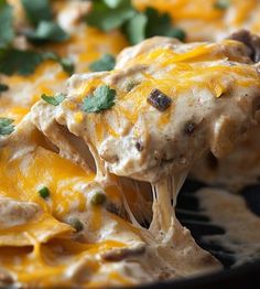 a close up of a spoon full of food with cheese and green garnish