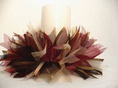 a white candle with red and gold ribbons around it