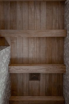 an empty wooden shelf in the corner of a room