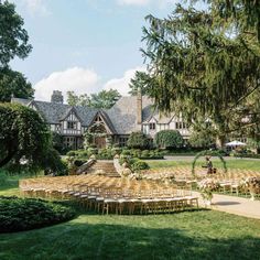 an outdoor ceremony setup with chairs and tables in front of a large house on a sunny day