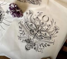 some paper with drawings on them sitting on a table next to a rock and crystals