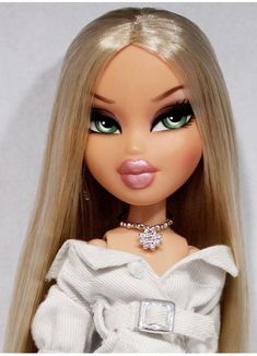 a close up of a doll with blonde hair and green eyes wearing a white dress