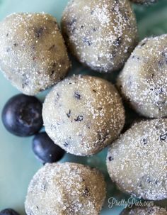 blueberry donuts with powdered sugar are on a plate next to blackberries