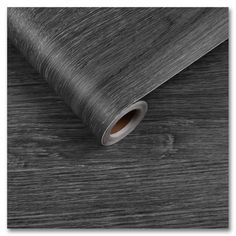 black and white woodgrain wallpaper with a roll of paper on the floor