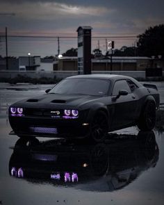 a black sports car with purple lights on it's hood parked in the rain