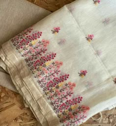 two pieces of cloth with flowers on them sitting next to some wood chips and a piece of fabric