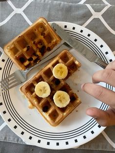 two waffles on a plate with bananas cut in half and a fork next to them